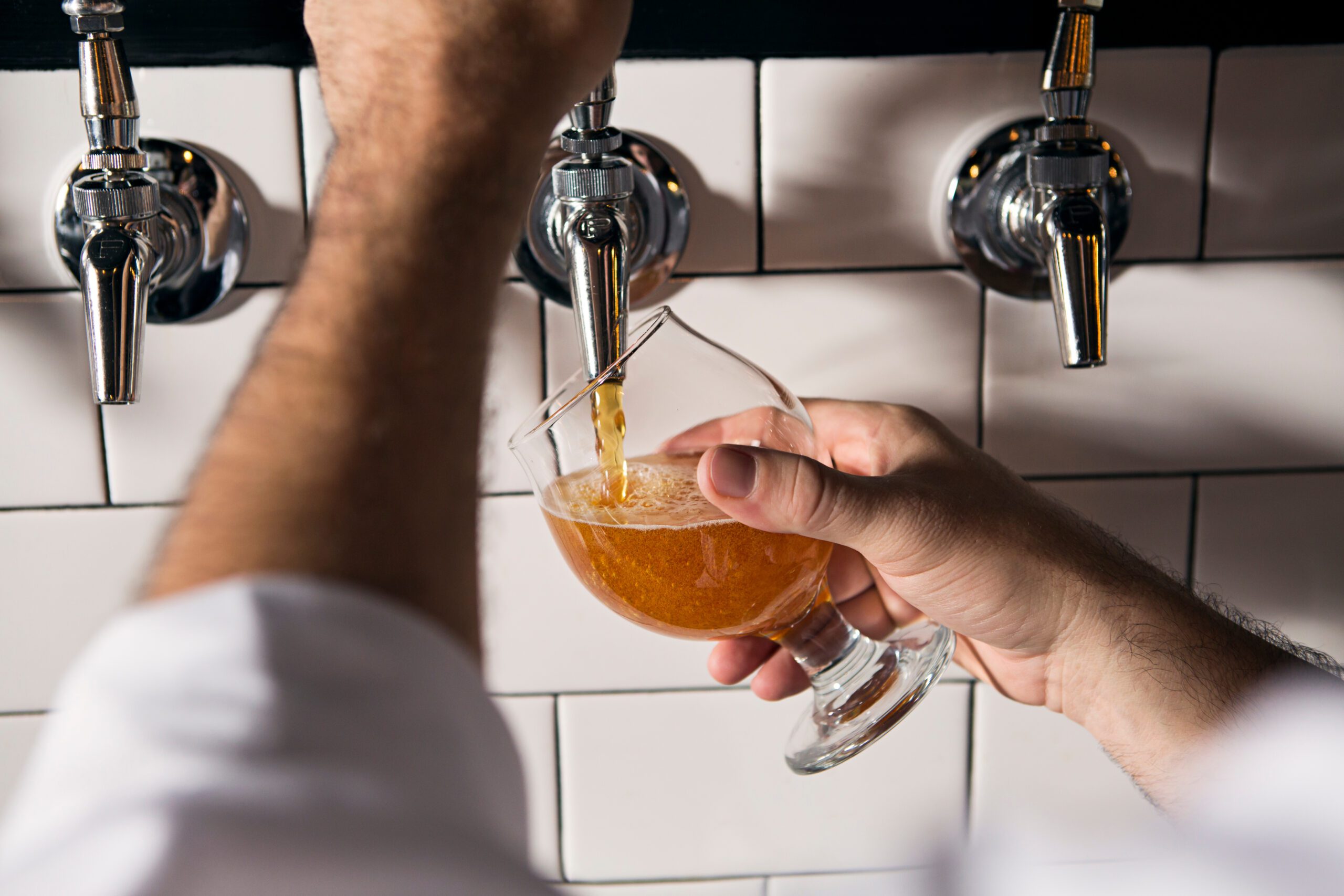 A bartender pours a beer at an upscale bar.